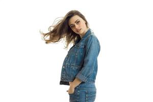 charming young girl in jeans jacket looks straight and her hair fly through the air photo