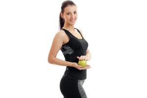 joyful slim girl stands in a sports suit and holding a Green Apple photo