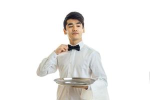 young cute waiter adjusts his bow tie photo