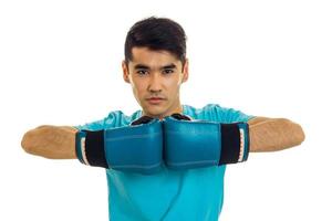 young strong man in blue shirt practicing boxing in gloves isolated on white background photo