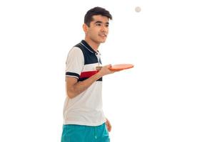 a young guy in a bright t-shirt stands sideways and holding a tennis racket isolated on white background photo