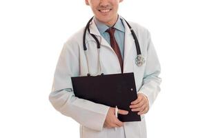 retrato de un joven médico alegre con uniforme blanco sonriendo a la cámara con estetoscopio en el cuello aislado en un fondo vacío. foto sin ojos