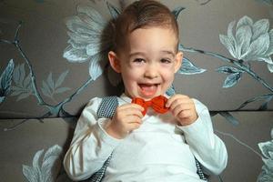 happy young boy with red bowtie in his hands photo