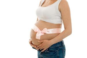 pregnant woman with pink tape on her big belly posing isolated on white background photo