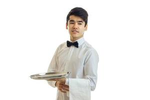 remarkable young waiter looks away smiling and holding a food tray and a towel photo