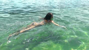 una joven delgada nada en el mar con traje de baño a rayas video