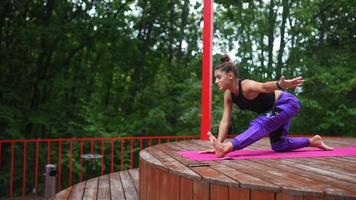 kvinna utför yoga poser och sträckor på utomhus- skede video