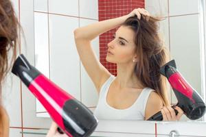 young cute girl in shower stands opposite the mirror and dries hair photo