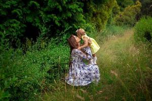 madre elegante feliz que lleva a su pequeña hija al aire libre foto