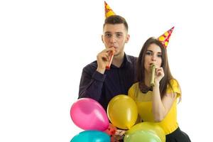 beautiful young couple holding colored balloons and blow horns photo