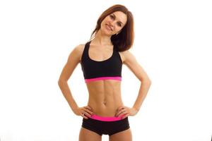 a charming young fitness girl with elastic tummy looks into the camera keeps your hands on the sides and smiling photo