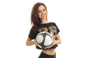 hermosa niña sonriente en una camisa deportiva sostiene la pelota y mira a una cámara foto
