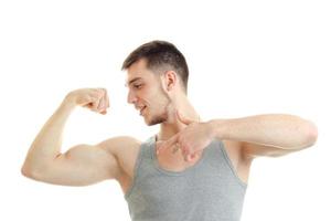 young sporty guy shows muscle on his hand and smiling isolated on white background photo