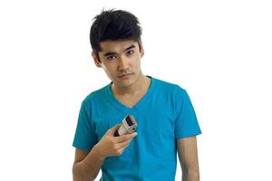 young cute guy in the blue shirt stands up straight and holding a Clipper to shave photo