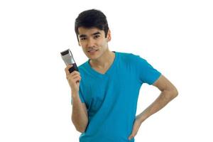 the charming, smiling guy in a t-shirt with the shaving machine keeps a hand on the side of smiling and looking at camera photo