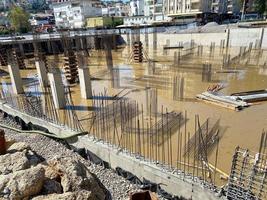 Construction of a monolithic-frame building, unfinished foundation with reinforced concrete columns at a construction site with a flooded pit photo