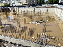 Construction of a monolithic-frame building, unfinished foundation with reinforced concrete columns at a construction site with a flooded pit photo