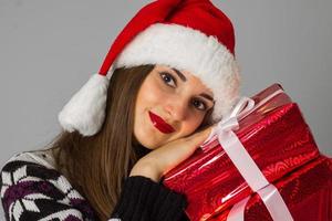 mujer en suéter cálido y sombrero de santa con regalo rojo foto