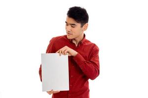 a young guy in a red shirt holding a white sheet of paper photo