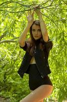 young beautiful girl in black jacket withour bra under it posing outdoors photo