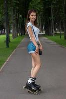 beautiful smiling girl in denim shorts rollerblading photo