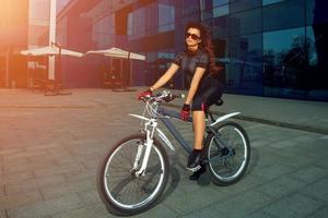 linda morena deportista con gafas de sol en bicicleta foto