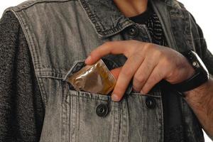 man gets out a condom of his pocket photo