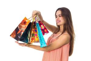 young girl with long hair stands sideways and rose in the hand of the beautiful colored packages close-up photo