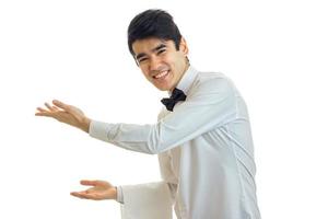 joyful handsome waiter reaches out his hands forward and invites people photo