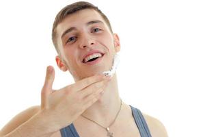 a close-up portrait of young cheerful guy with shaving foam on the Palm of your hand photo