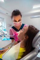 dentista con uniforme rosa trata los dientes de un paciente foto