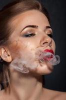 hembra adulta de belleza fumando en el estudio foto
