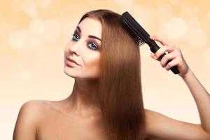 Attractive adult caucasian girl with blue eyes combing her perfect brown healthy streight hair with comb photo