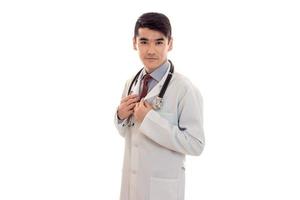 a young doctor in a white lab coat with a stethoscope looks at camera photo