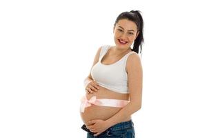 cheerful pregnant brunette woman with pink tape on her big belly posing isolated on white background photo