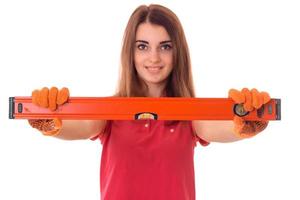 happy young brunette builder girl in uniform makes renovation with tools in her hands isolated on white background photo