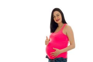 happy pregnant future mother in pink shirt showing thumbs up isolated on white background photo