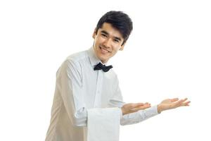 handsome young waiter smiling tilting his head and extends two hands towards photo