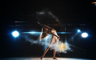 bailarina sexy en el escenario posando contra el telón de fondo del centro de atención foto