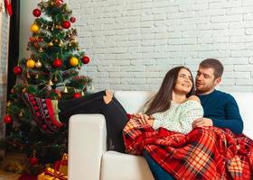 Nice couple in love lies on a couch wrapped in plaid Christmas Eve photo