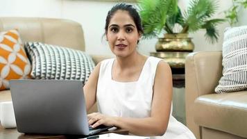 video de archivo de una mujer india sonriente que trabaja en una computadora portátil.