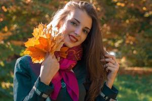 beautiful girl smiling looking forward and keeps the leaves close-up photo
