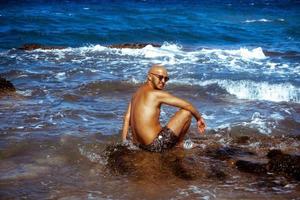 young tanned guy on the Rocky seashore photo