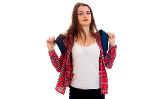 young tired brunette student girl with backpack on her shoulders posing and looking at the camera isolated on white background photo