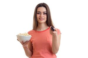 charming young girl smiling and holding a pop-corn and the remote from the tv photo