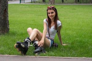 happy beautiful young girl sitting on the grass in rollers photo