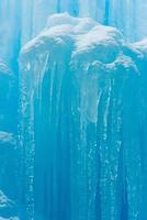 Translucent blue icicles in a frozen ice wall. photo