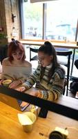 Young women in a cafe talking and using laptop video