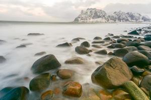 olas que fluyen sobre la playa de utakleiv, islas lofoten, noruega en el invierno. foto