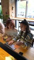 Young women in a cafe talking and using laptop video